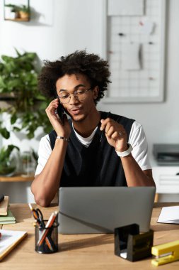 Genç Afrikalı Amerikalı adam evde çalışırken telefonda hevesle konuşuyor..