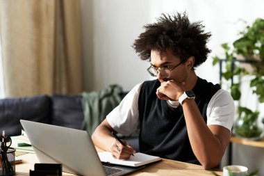 Genç adam masasına notlar yazarken şık ve rahat bir yaşam alanına yansıyor..