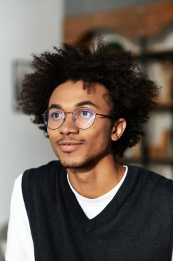 Tarz sahibi, kıvırcık saçlı, modern dekorasyon ve konforla çevrili evinde rahatlayan genç bir adam..