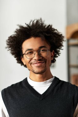 Genç bir Afrikalı Amerikalı adam şık, rahat oturma odasında sıcacık gülümsüyor..