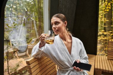 Beyaz bornozlu güzel bir kadın spa merkezinde rahatlık ve sükunetin tadını çıkarıyor..