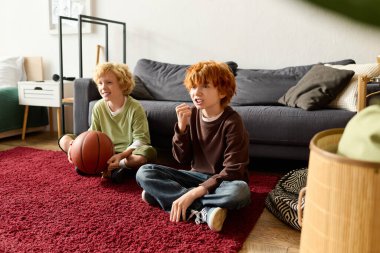 İki heyecanlı çocuk modern dairelerinde basketbol maçı izleyip birlikte vakit geçiriyorlar..