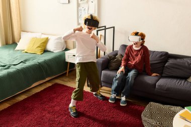 İki mutlu çocuk, sıcak bir oturma odasında sanal oyunlar oynayarak eğleniyor..