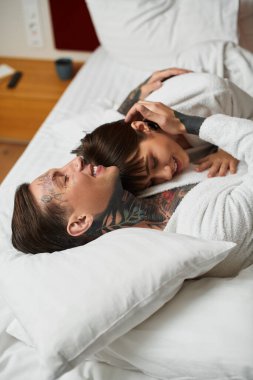 Neşeli bir çift bir otel odasında dinlenirken birbirlerine sarılır, sevgi ve sıcaklık saçar..