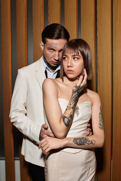 Couple stands closely together in an elegant hotel room, sharing a moment of tenderness.