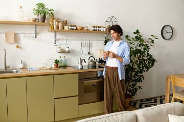 Yakışıklı genç adam şık mutfağında huzur içinde sıcak bir içki yudumluyor..