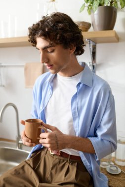 Genç bir adam dairesinde dinleniyor, kahvesini yudumluyor ve sakin atmosferin tadını çıkarıyor..