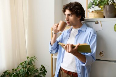 Genç bir ortadoğulu adam evinde dinleniyor, çayını yudumluyor ve pencere kenarında kitap okuyor..