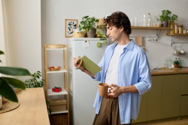 Kıvırcık saçlı genç bir adamın elinde fincanla kitap okuması zaman alır..