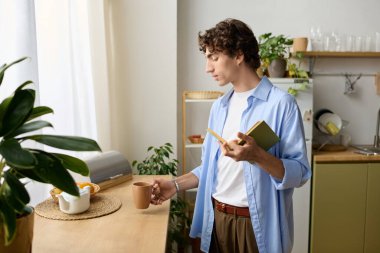 Yakışıklı genç adam rahat dairesinde duruyor, düşüncelerini yazarken kahvenin tadını çıkarıyor..