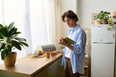 Genç bir ortadoğulu adam, rahat dairesinde çay içerken sakin bir sabah kitap okuyarak geçirir..