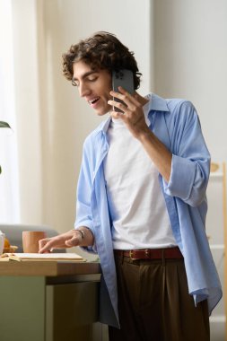 Ortadoğulu genç bir adam evinde ders çalışırken telefonla konuşuyor..