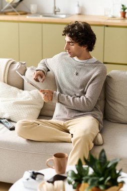Yakışıklı genç bir adam evde rahatlıyor, rahat dairesinde dergi okuyor..