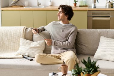 Orta Doğulu genç bir adam rahat bir kanepede dinleniyor, evde boş zaman aktiviteleriyle meşgul..