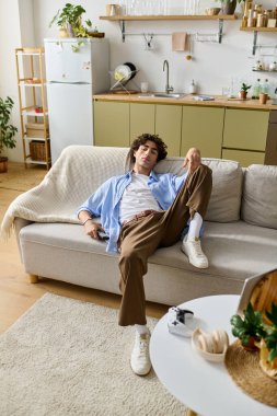 Kıvırcık saçlı yakışıklı genç adam evindeki kanepede rahatça dinleniyor..