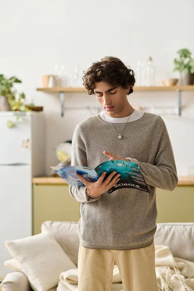 Kıvırcık saçlı yakışıklı genç adam evde rahatlıyor, bir dergiye odaklanıyor..