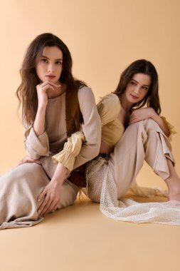 İki şık ikiz kardeş rahat bir stüdyoda, benzersiz kıyafetlerini sergiliyorlar..