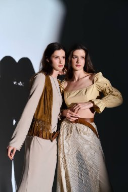 Genç ikiz kardeşler zarif bir şekilde poz verirler, şık kıyafetler, ışıl ışıl güzellik ve tarz..