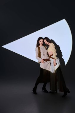 İkiz kardeşler şık kıyafetler giyip göz alıcı bir sahnede kendine güven ve güzellik yayıyorlar..