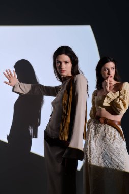 İkiz kardeşler şık kıyafetler içinde şık poz verirler. Eşsiz tarzlarını arka planda gösterirler..