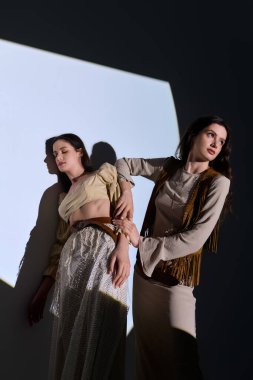 Güzel ikiz kardeşler, yaratıcı bir ışık ortamında poz verirken moda anlayışlarını sergilerler..