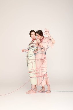 İki güzel ikiz kız kardeş moda anlayışlarını sergilerken neşeli bir şekilde kıvrılırlar..