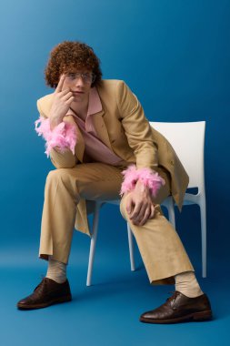 Genç bir çocuk hareketli bir poz veriyor, moda giyiniyor, renkli bir şekilde stüdyo ortamında.