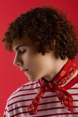 Genç çocuk kendine güveni tam duruyor, moda kıyafetini göz alıcı bir eşarpla vurguluyor..