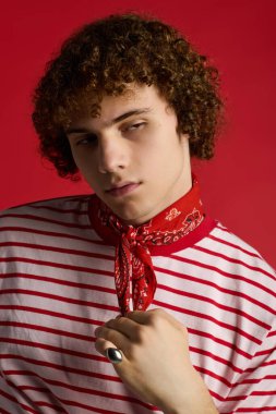 Şık bir çocuk, kendine güveni tam kırmızı bir ortamda, modaya uygun kıyafetini sergiliyor..