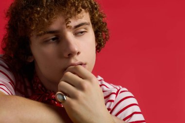 Genç çocuk şık çizgili kıyafetler içinde özgün bir tarz ve enerji yayarak düşünceli bir şekilde poz veriyor..