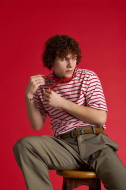 Şık bir genç, kendine has modasını canlı bir ortamda sergileyerek poz verir..