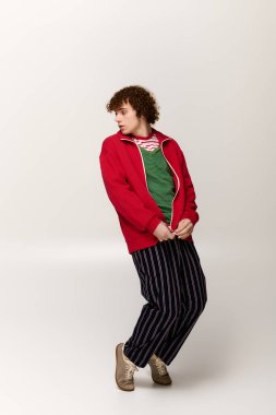 Tarz sahibi genç bir çocuk, canlı enerji ve yaratıcılığını ifade eden modaya uygun giysiler içinde duruyor..
