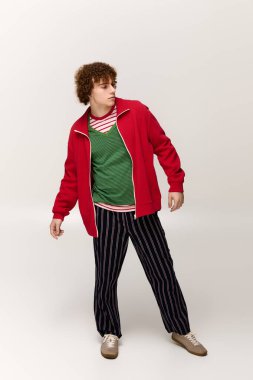 Genç çocuk kendine has tarzını canlı bir pozla ifade ediyor, şık kıyafetinin altını çiziyor..