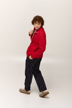 Genç çocuk modada aktif bir poz sergiliyor, modern modayı temiz bir zeminde somutlaştırıyor..