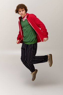 Bir çocuk basit bir arkaplana karşı zevkle modaya uygun kıyafetler giyer..