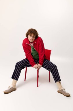 Gençler dinamik bir şekilde sandalyede poz veriyor, eşsiz moda ve enerjik tarz seçimlerini vurguluyorlar..