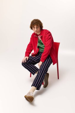 Şık bir genç, çarpıcı bir şekilde genç enerjisini ifade ederek dinamik bir duruş sergiliyor..