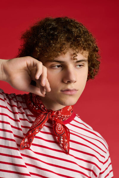 A stylish teenager poses thoughtfully, showcasing a trendy outfit that highlights his fashion sense.