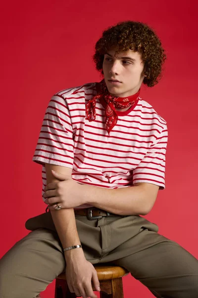 Genç dinamik pozlar veriyor, şık çizgili gömlek ve kırmızı bandana giyiyor..