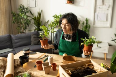 Genç bir çiçekçi mutlu bir şekilde masasında filizleniyor, doğal güzelliklerle çevrili..