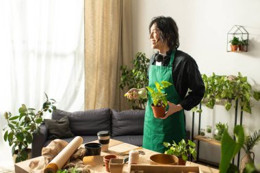 Neşeli çiçekçi, sakin bir bahçe düzenine daldırılmış canlı bir saksı saksısı tutuyor..