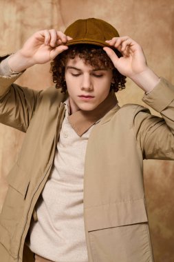 Yakışıklı genç şık şapkasını düzeltiyor, modaya uygun bir görünüm ve kendine güvenen bir tavır sergiliyor.