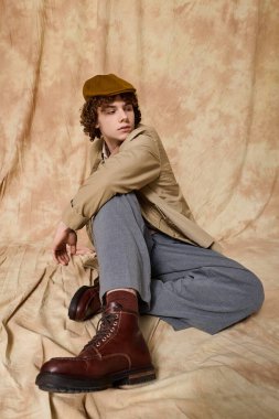 Yakışıklı bir genç rahat bir şekilde oturur, düşünceli bir ifadeyle moda modasını sergiler..