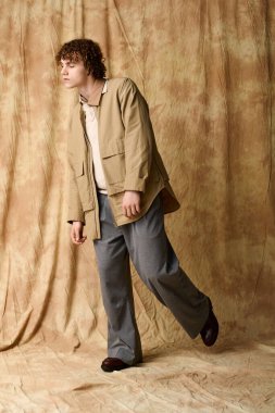 Şık bukleli bir genç, sıcak bir stüdyoda modern moda sergiliyor..