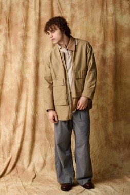 Yakışıklı bir genç zarif bir zemin üzerinde duruyor, modern moda sergiliyor..