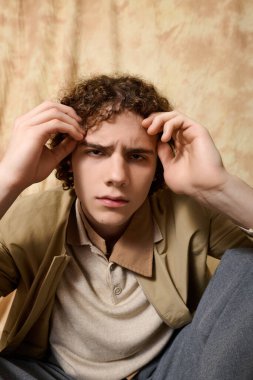 Şık genç adam, düşünceli ifadesiyle yumuşak tonlarda dikkat çekiyor..