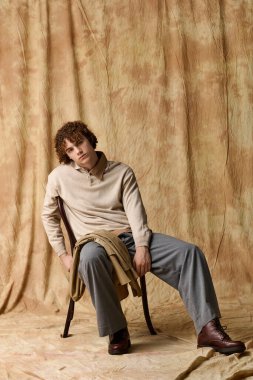 Yakışıklı genç, rahat bir stüdyoda özgüvenle poz veriyor, modern stili yetenekle kucaklıyor..