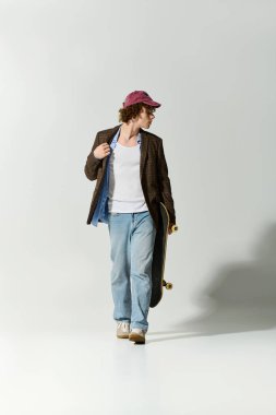 Şık giyinmiş yakışıklı genç adam elinde kaykayla güven içinde geziyor..