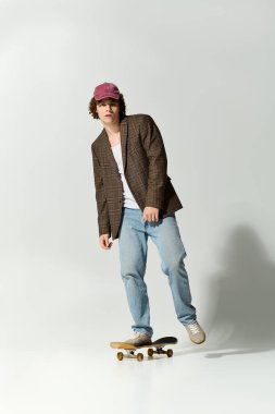 Yakışıklı bir genç, şık bir görünüm sergilerken kaykayla numaralar yapıyor..