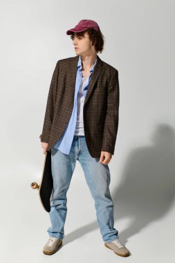 Yakışıklı genç rahat bir şekilde günlük kıyafetlerle stüdyoda duruyor, stil ve konfor dengeliyor..